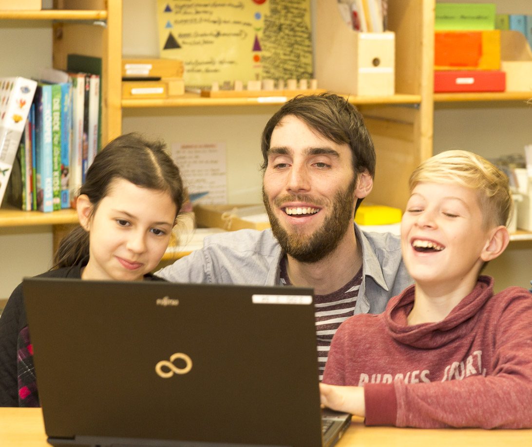 Lehrer und Schülergruppe am Laptop